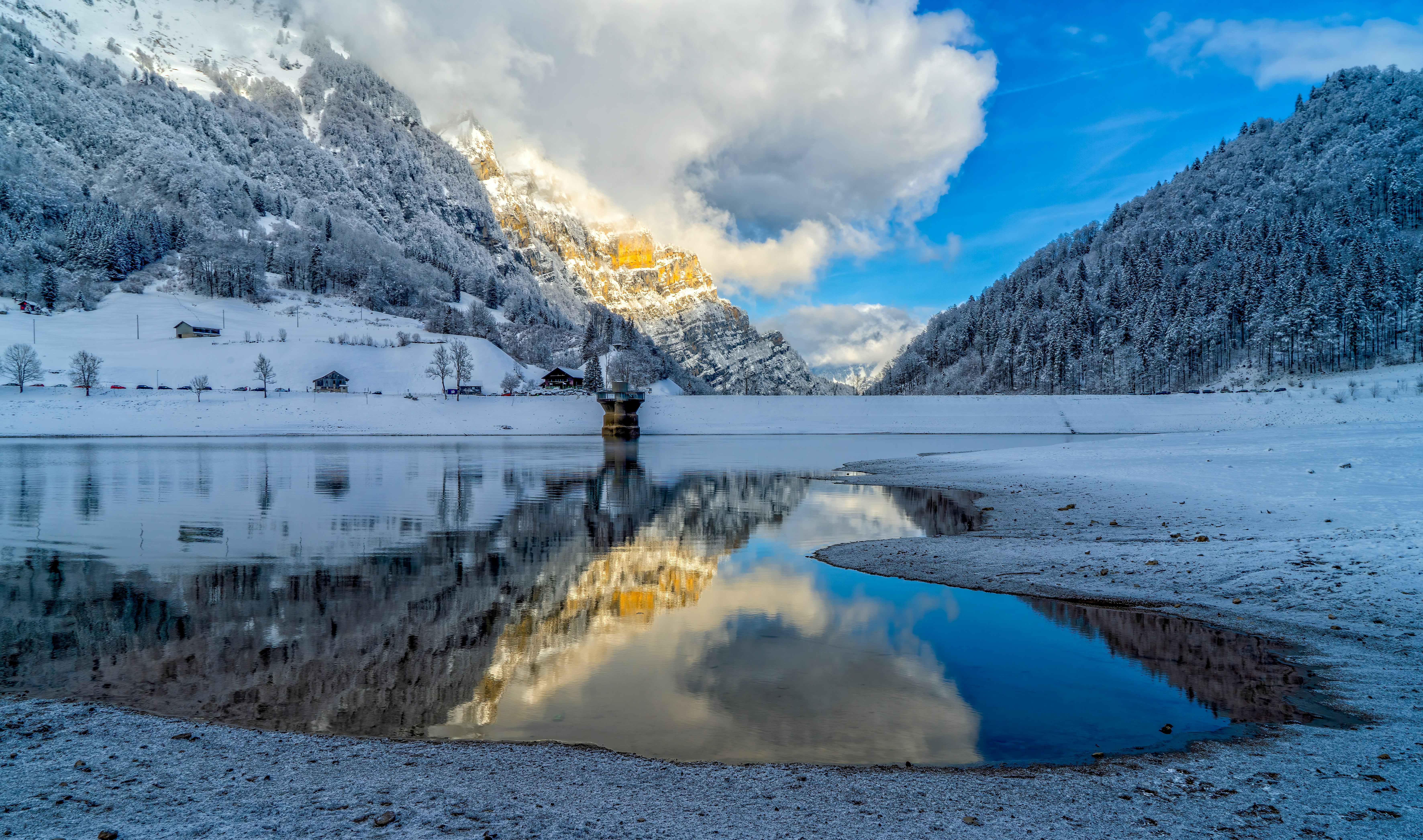 snow covered mountain near body of water during daytime